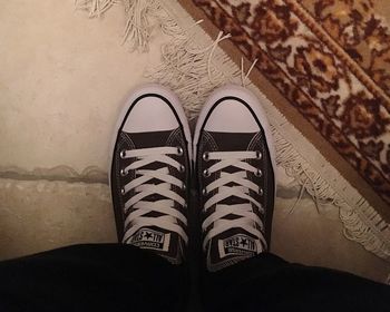 Low section of person wearing canvas shoes at home