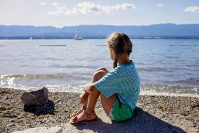 Girl looking at sea sitting on rock