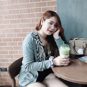 Portrait of a smiling young woman sitting against wall