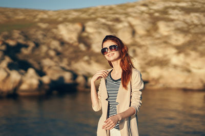 Portrait of young woman wearing sunglasses standing outdoors