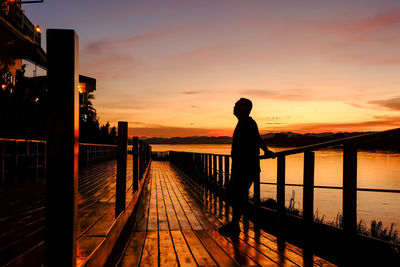 Man on pier against sky during sunset