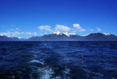 Scenic view of sea and mountains against blue sky