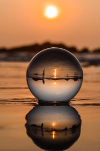 Close-up of illuminated lamp at beach against sky during sunset
