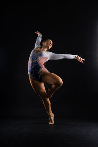 Full length of woman jumping against black background