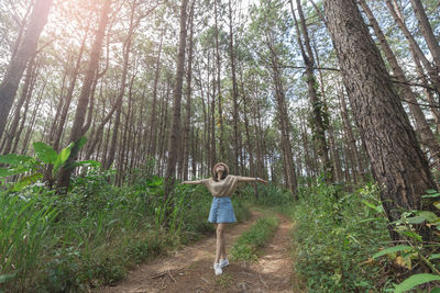 Young woman with arms outstretched standing in forest