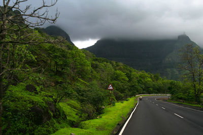 Road amidst green mountains against sky