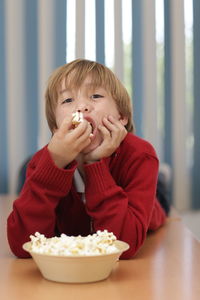 Portrait of playful boy eating popcorns at home