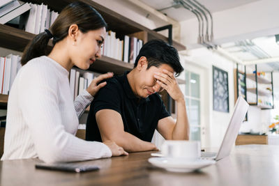 Depressed businessman sitting with woman at office