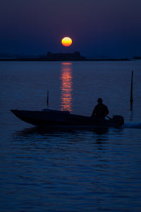 Silhouette man in sea against sky during sunset