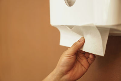 Close-up of hand holding paper against wall