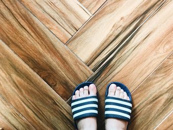 Low section of woman standing on wooden floor