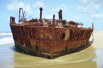 Abandoned boat on sea against sky