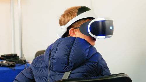 Rear view of boy using virtual reality simulator