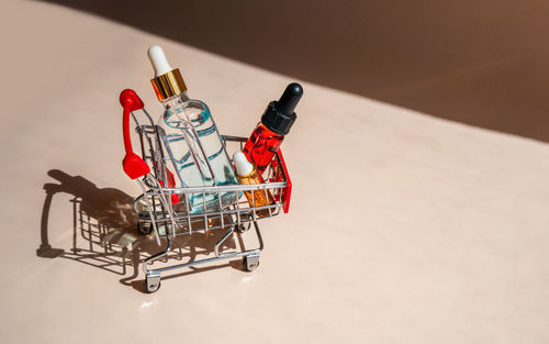 Online shopping minimalistic concept. small cart with cosmetic bottles. essential oil, serum 