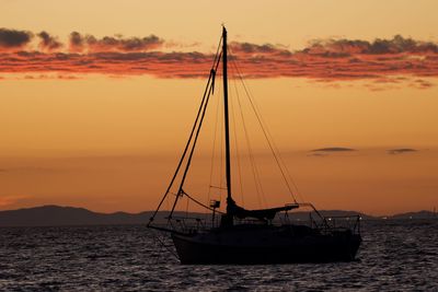 Silhouette sailboat on sea against sky during sunset