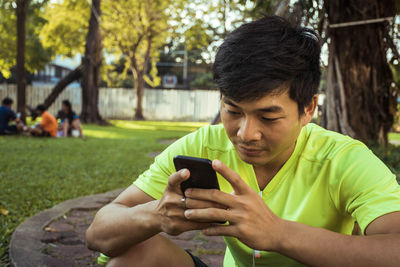 Side view of young man using mobile phone in park