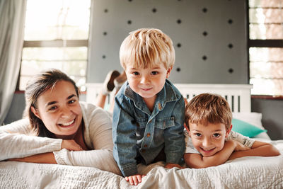 Portrait of mother and sons lying on bed at home