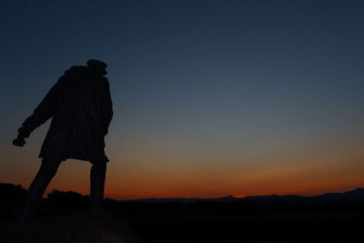 Silhouette man standing against clear sky during sunset