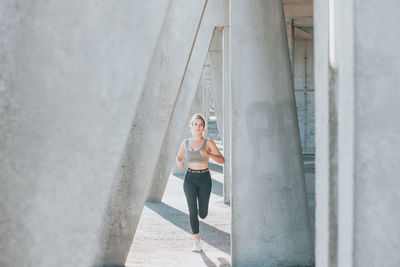 Female athlete running between column