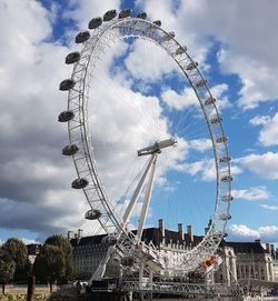 Low angle view of ferris wheel against cloudy sky