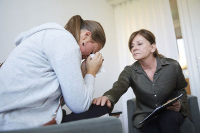 Senior therapist consoling depressed teenage girl at workshop