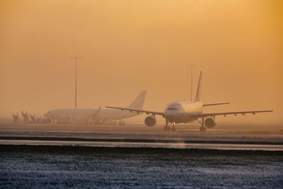 Airplane flying against sky during sunset