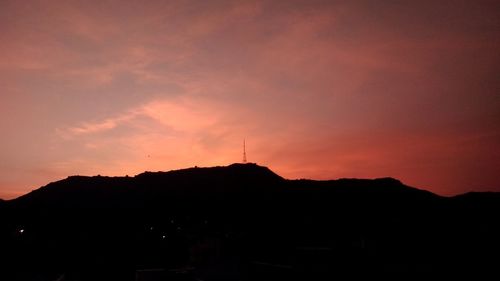 Silhouette buildings against dramatic sky during sunset