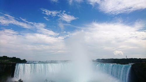 Waterfall against cloudy blue sky