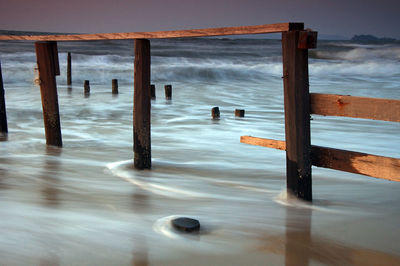 Wooden posts on beach against sky