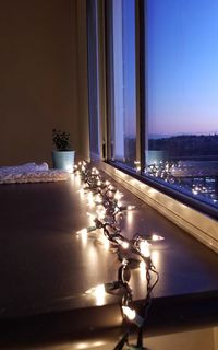 Lamp on glass window against illuminated building