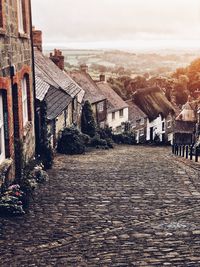 Street amidst houses in town against sky