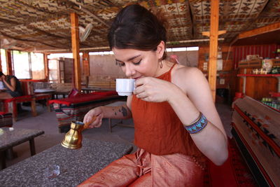 Young woman drinking coffee in tent