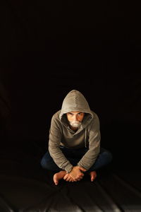 Man sitting against black background