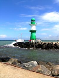 Lighthouse on groyne in sea against sky