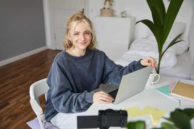 Young woman using digital tablet while sitting on sofa at home