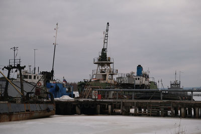 Cranes at harbor against sky