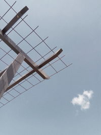 Low angle view of crane against building against sky