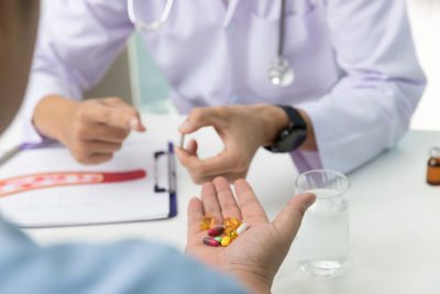 Midsection of doctor giving medicine to patient at clinic