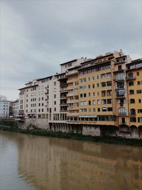 Buildings by river against sky in city