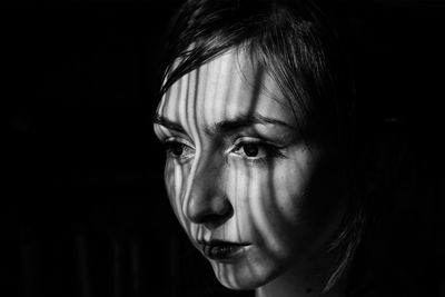 Close-up portrait of a young woman over black background