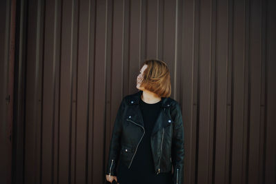 Young woman standing against wall