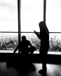 Silhouette man and woman standing by window