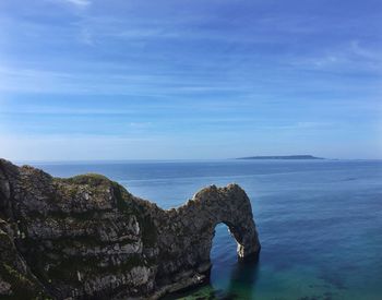 Rock formation in sea against blue sky