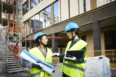 Female engineer discussing with coworker while standing at construction site