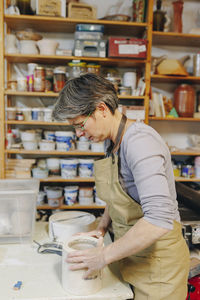 Mature potter with ceramics working at workshop