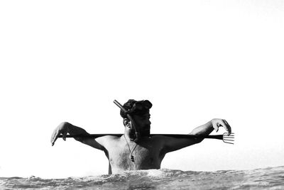 Man with spear in sea against clear sky