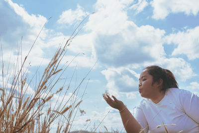 Low angle view of woman holding plants against sky