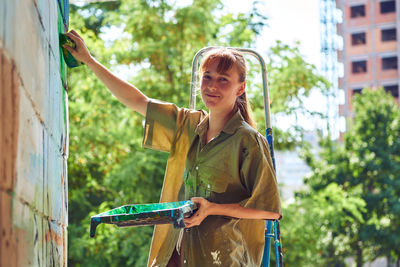 Portrait of young woman standing against trees