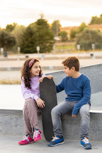 Two kids with a skate board at sunset