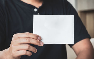 Midsection of man holding paper